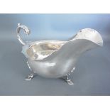 A hallmarked silver sauce boat raised on three pad feet with foliate scroll handle - Weight approx.