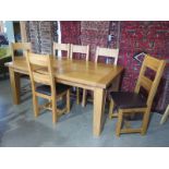 An oak extending dining table with a folding leaf and six leather seated ladder back chairs -