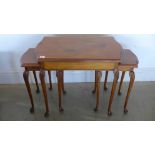 A nest of three tables, serpentine edged and raised on slender supports terminating in pad feet,