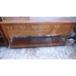 An oak pot cupboard dresser base of three drawers over shaped apron above shelf raised on turned