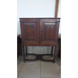 An oak two door cupboard on a sugar barley twist stand with a fitted interior of pigeon holes and