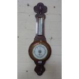 A carved oak aneroid barometer with thermometer retailed by Sidney Campkin and Sons Cambridge -