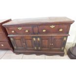 An 18th century oak dresser base with two drawers over two panelled cupboard doors raised on