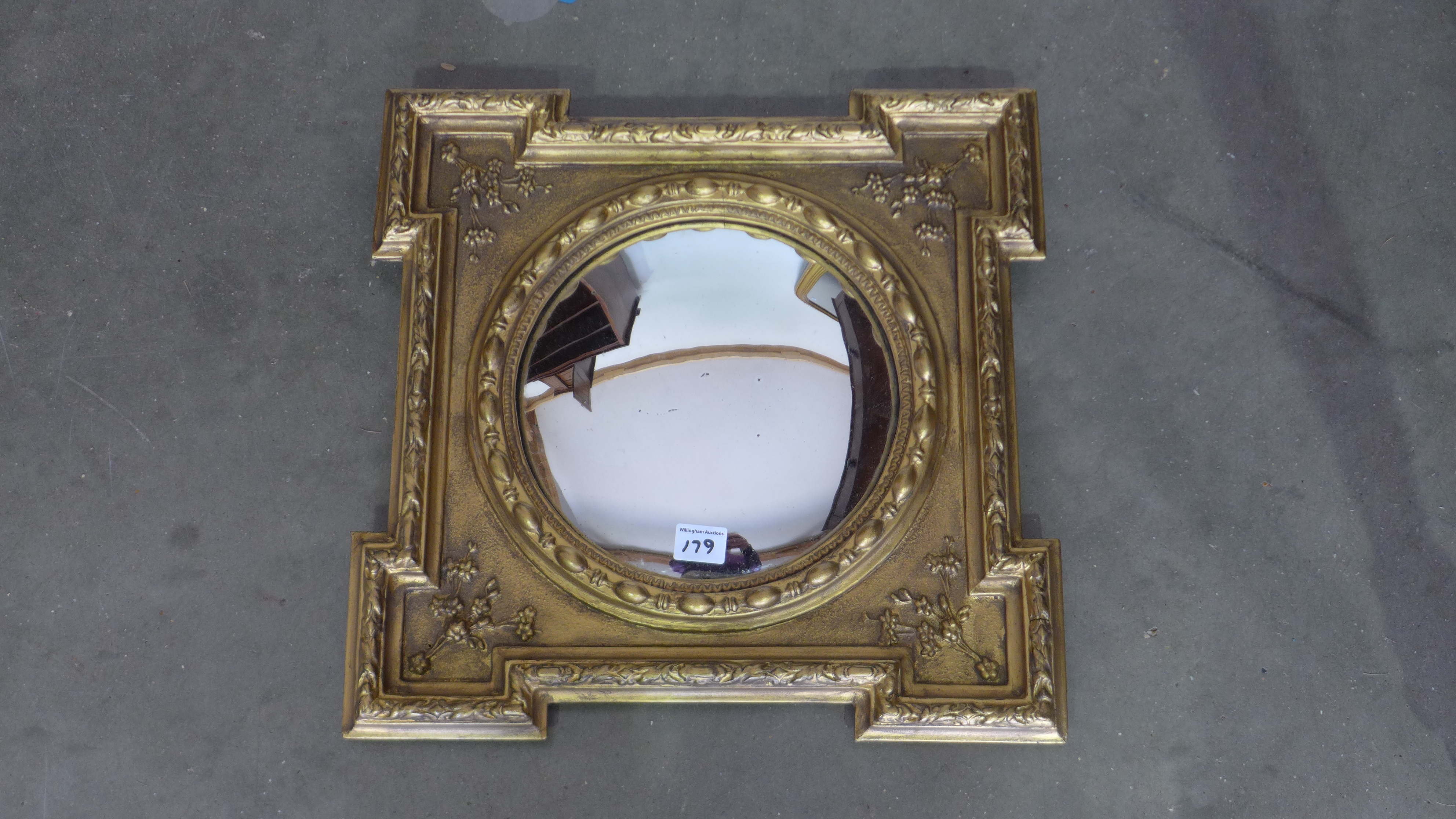 A small gilt mirror with round glass and decoration - 43cm x 43cm