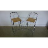 A pair of modern chrome stools with light beech seats