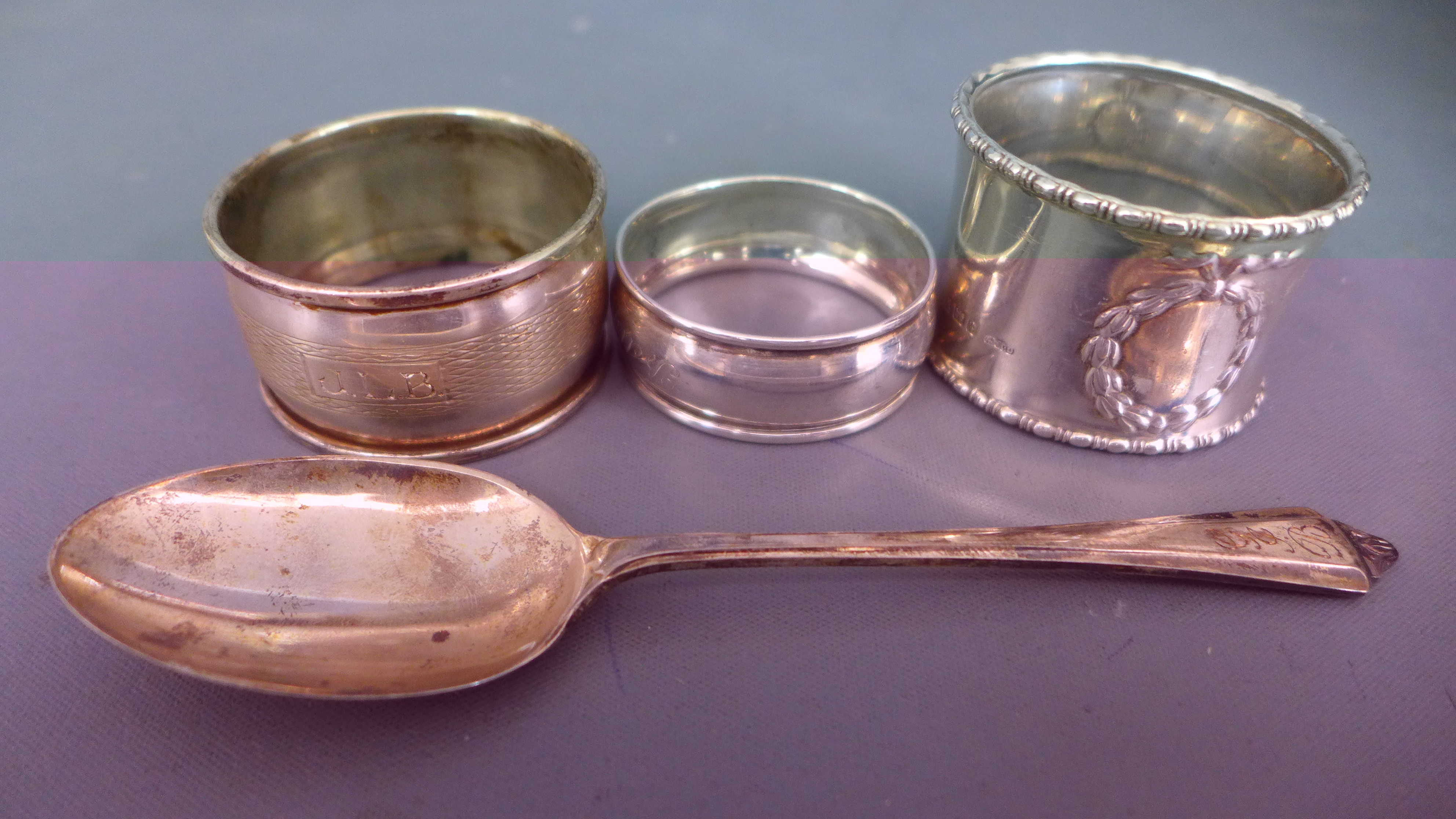Three silver hallmarked napkin rings and a silver hallmarked teaspoon - approx weight 1.