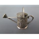 A Continental silver miniature watering can with embossed figural design