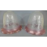 A pair of etched glass lamp shades with ruby coloured edge,