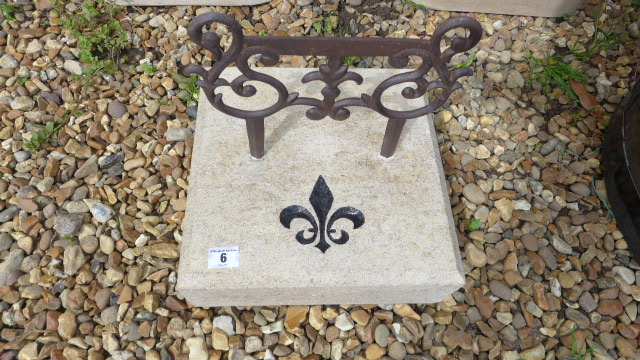A boot scraper with limestone base and a hand carved and painted Fleur de Lys motif on front