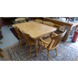 A pine kitchen table, extendable with extra leaves below centre,