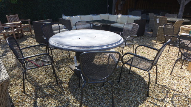 A Bramblecrest round stone table with six chairs and cushions