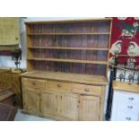 A 19th century stripped pine dresser with an open rack top on a three drawer four door base -