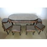 A very large heavily carved Chinese camphor wood coffee table with six stools or tables to rest