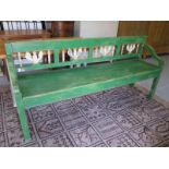 A 19th century bench, with old green paint, shaped arms,
