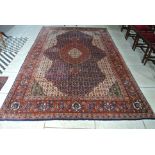 A hand knotted woolen rug with a central medallion and stylized border - 330cm x 207cm