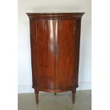 A mahogany two door quarter cylinder cupboard with shelved to interior raised on later turned