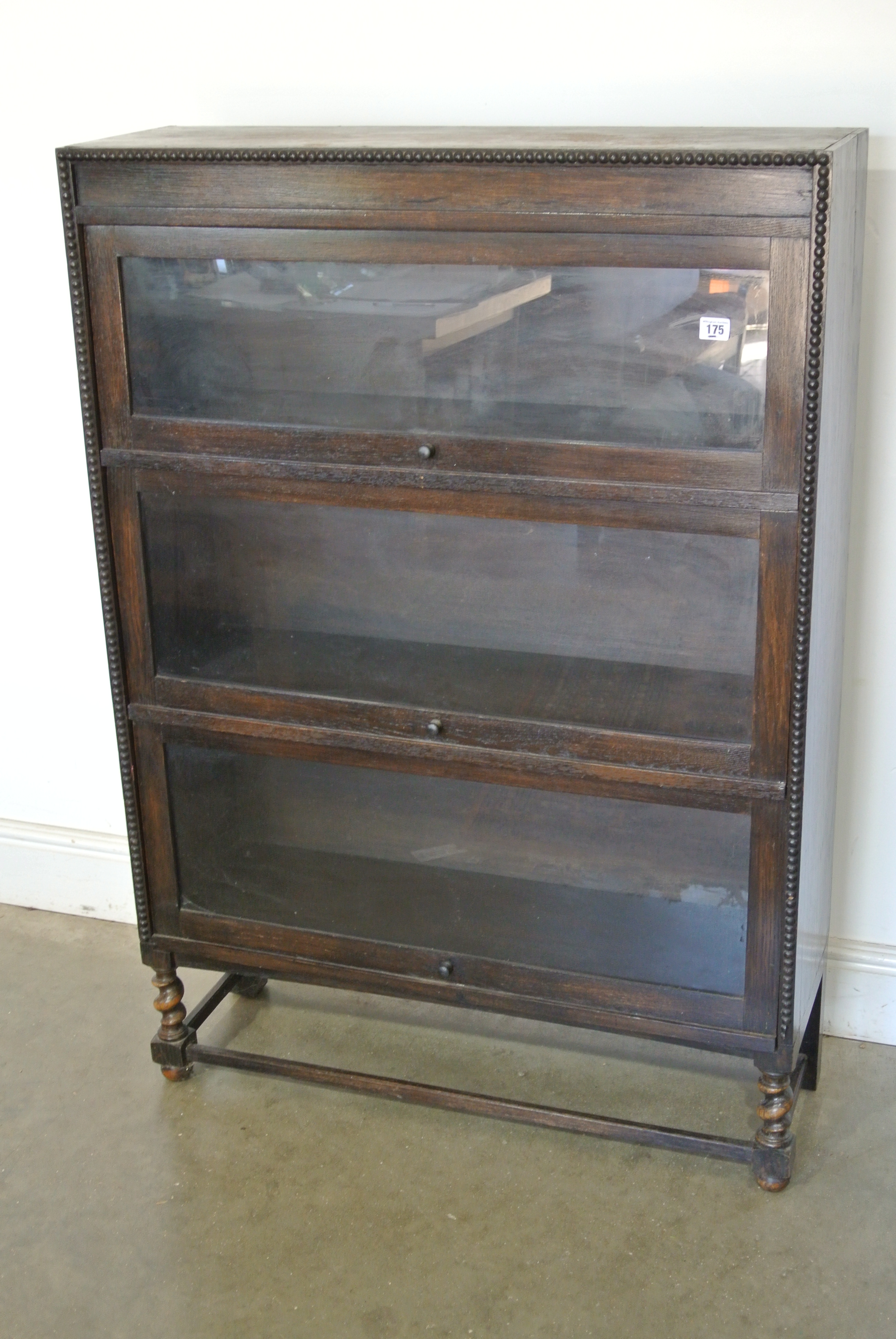 An oak glazed bookcase with three glazed lift up doors - Height 124cm x 86cm x 29cm