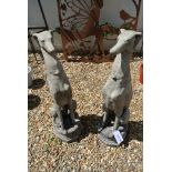 A pair of reconstituted stone seated whippets on a decorated octagonal plinth - Height 79cm