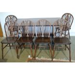 A dark stained oak trestle dining table and six wheelback dining chairs - Height 72cm x 80cm x