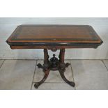 A Victorian burr walnut fold over card table with an inlaid ebonised top on a carved four pillar