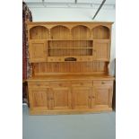 A modern pine dresser with a plate rack over the base with four drawers and four cupboard doors -