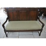 An 18th Century oak settle with a three panelled back and an upholstered seat
