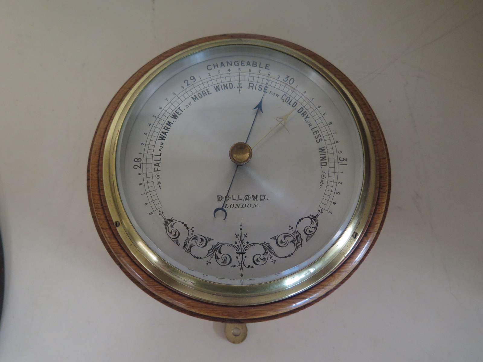 An oak cased aneroid bulkhead barometer by Dolland of London - 17cm diameter