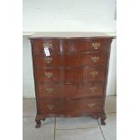 An Edwardian mahogany serpentine five drawer chest with blind fretwork canted corners on ogre