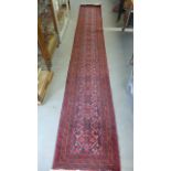 A hand knotted woollen runner with a red field - 393 cm x 62 cm - overall good condition - minimal