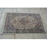 A Hand Knotted Woollen Rug with central medallion and cream field - 166 cm x 93 cm - some wear