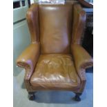 A Tan Leather Wingback Armchair on ball and claw feet with a feather filled seat