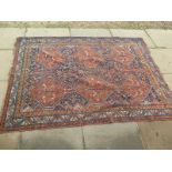 A hand knotted woollen rug with rust coloured field and geometric bird in tree design - 228 cm x