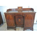 A Sheraton Revival Kneehole Desk with a gallery top above a blind drawer and three cupboard doors -