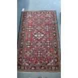 A small hand-knotted woollen rug wth a red field - 165 cm x 104 cm - some usage wear - mainly to