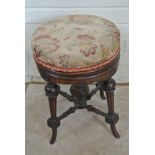 A Victorian turned wood piano stool raised on four splayed legs and having an upholstered revolving