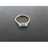 An 18ct yellow gold diamond and emerald three stone ring - size N - approximately 1.