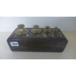 A set of 14 metric brass and metal weights from 2 kilograms to 1 gram - on a wooden block with