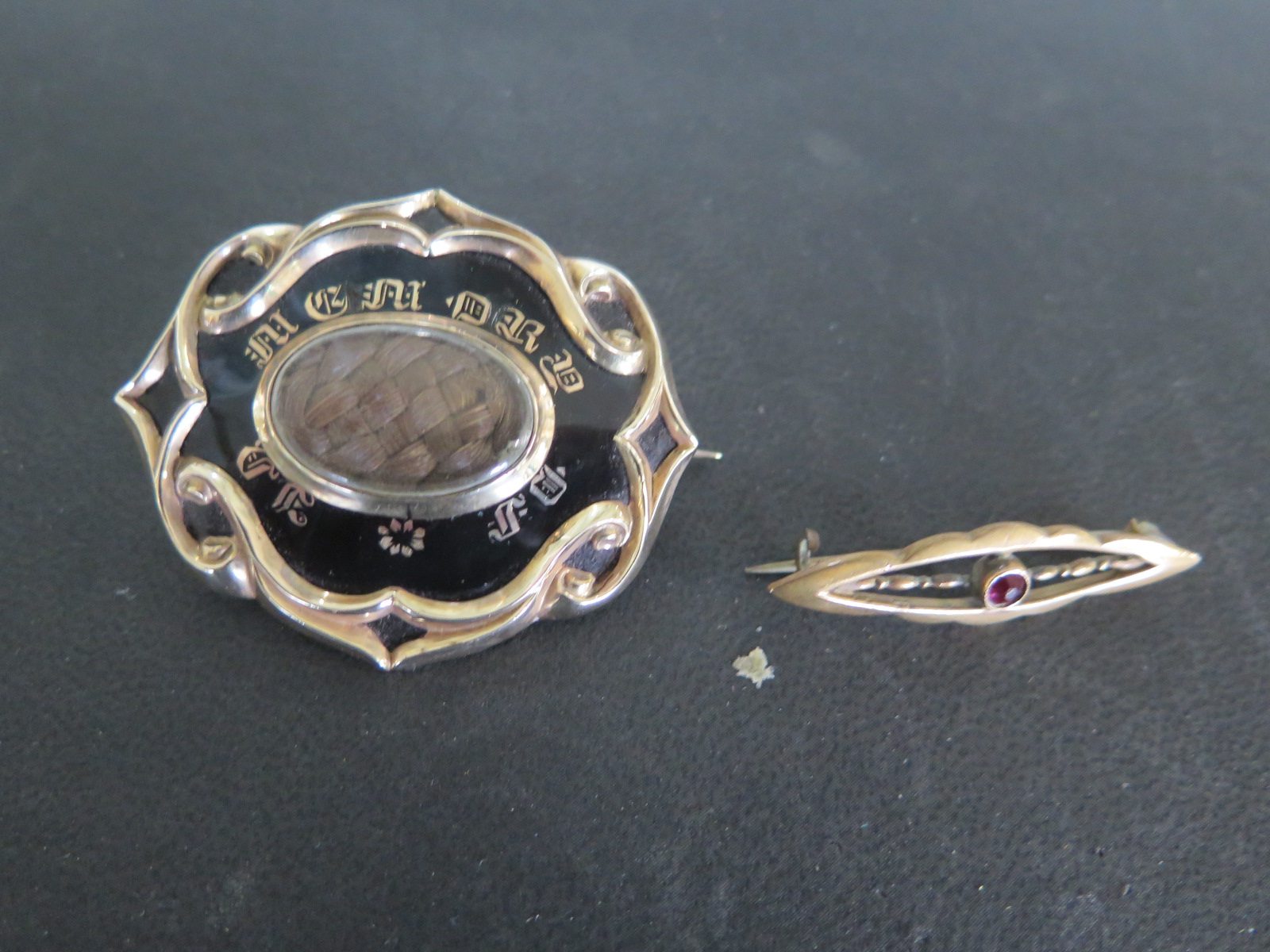 A presumed gold ornate hair and enamel mourning brooch inscribed F.B.