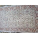 A hand knotted woollen rug with a cream field 210cm x 120cm