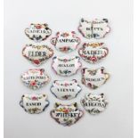 A collection of twelve enamel wine and toilet labels, cartouche and escutcheon form, with black