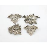 A small collection of four antique silver wine labels, various dates and makers, vine leaf form,