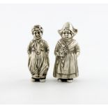 A pair of German silver novelty pepper pots, modelled as a Dutch boy and girl, heights 7cm and 6.