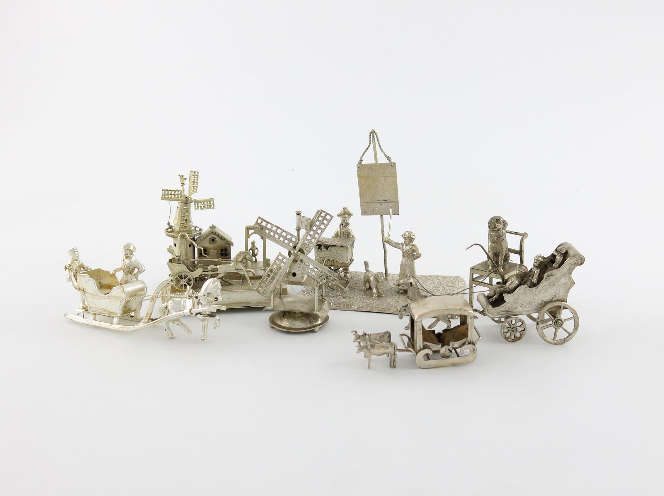 A small collection of silver miniatures, comprising figural groups: a windmill, canal and carriage