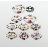 A collection of ten enamel wine and toilet labels, cartouche and escutcheon form, with black