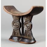 A Shona headrest Zimbabwe wood with two geometric carved supports flanking a central post on a facet