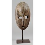 A Dan mask Ivory Coast wood, with nails, the forehead with a vertical ridge, 23cm high, on a