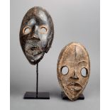 A Dan mask Ivory Coast wood, with large circular eyes and white pigment, 22cm high, and another