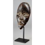 A Dan passport mask Ivory Coast wood, 18cm high, on a stand. (2) Provenance The David Morris