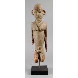 A Lobi male figure Burkina Faso wood, with an encrusted patina, wearing a triangular neckpiece, 43cm