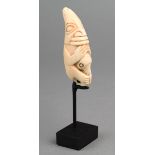 λA Tlingit amulet North West Coast marine ivory carved as a seated figure with a beak like head,